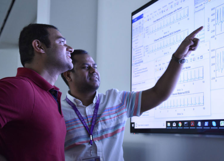 Two men pointing at a screen.