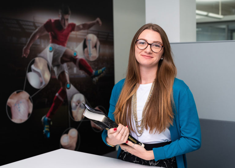 Light skinned female with glasses holding books.