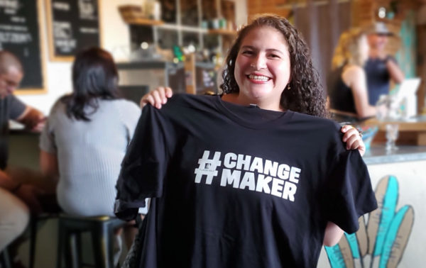 Alum holding a "changemaker t-shirt.