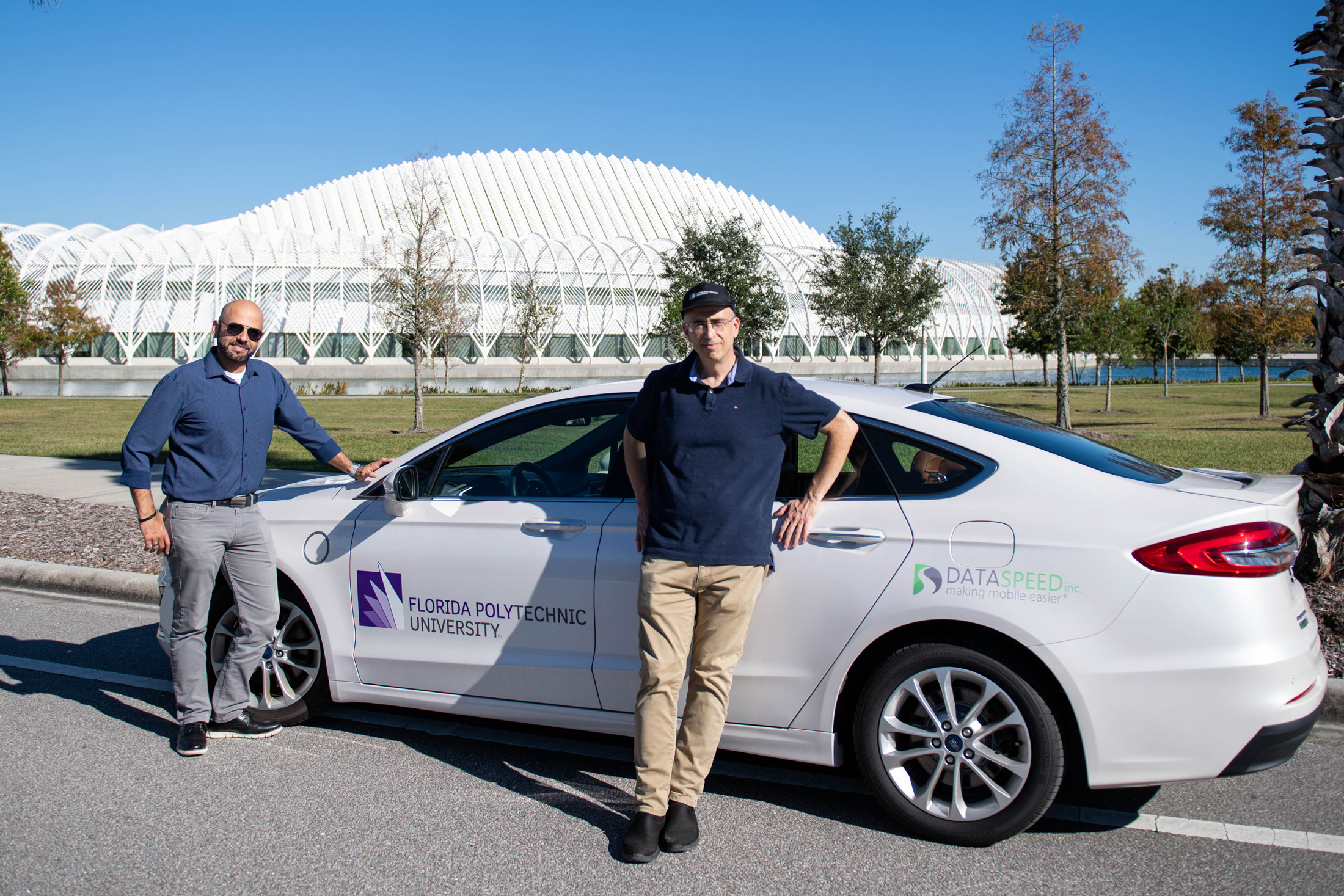 Dr. AJ Alnaser and Dr. Onur Toker stand alongside Florida Poly's new autonomous vehicle.