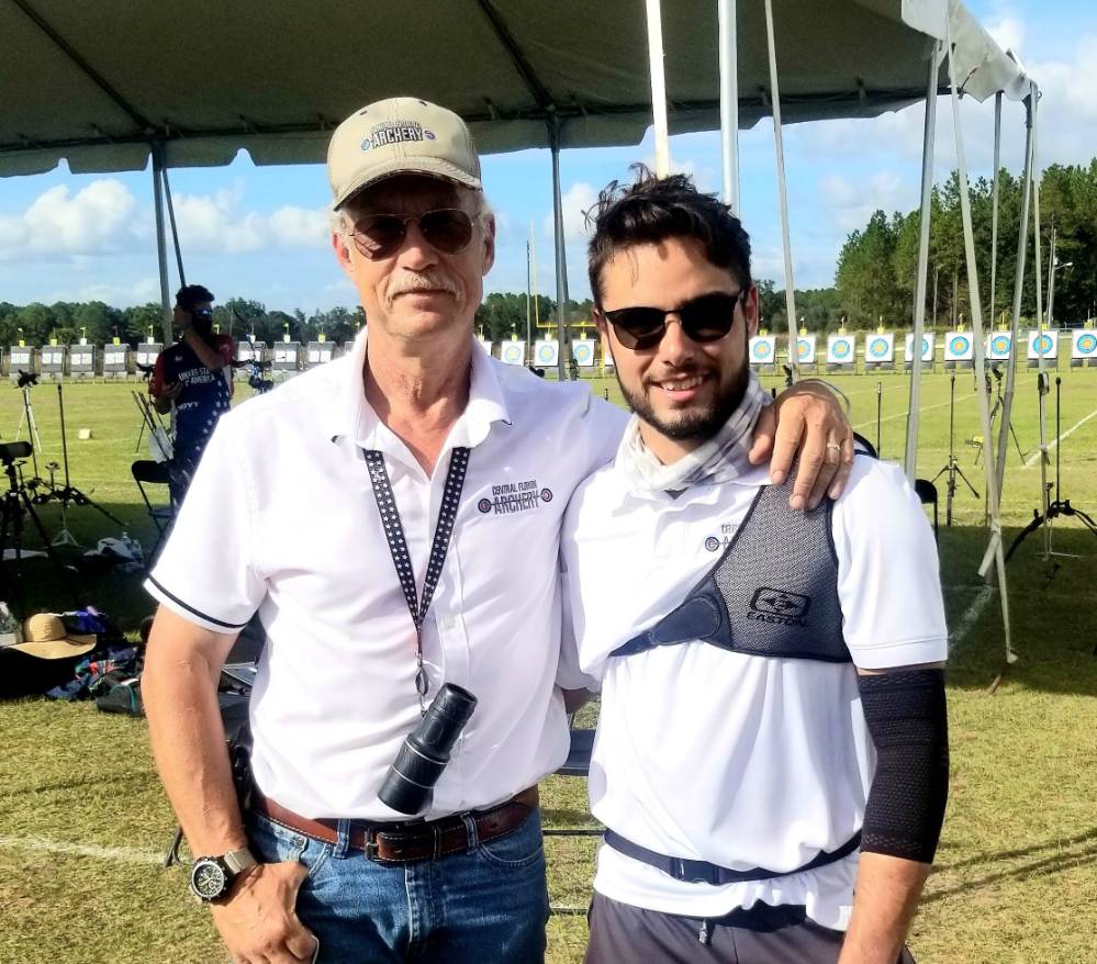 two males standing at archery range