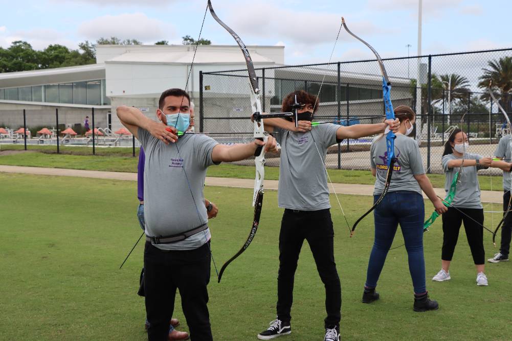 archery team with bows drawn on range