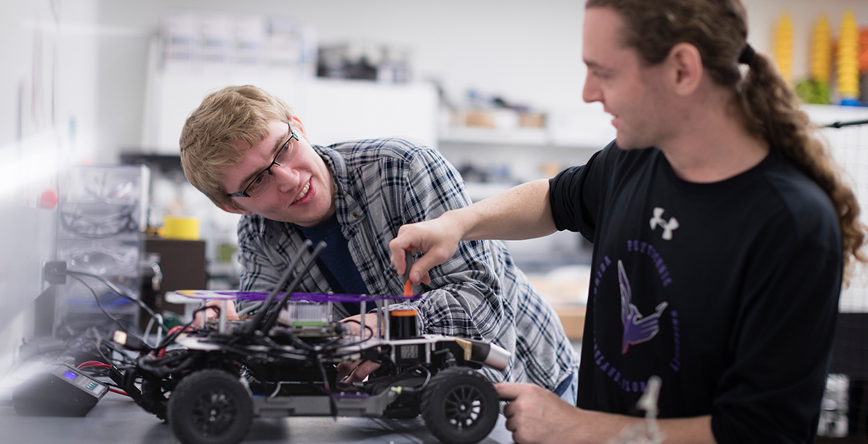 Two male students work on a robotics project