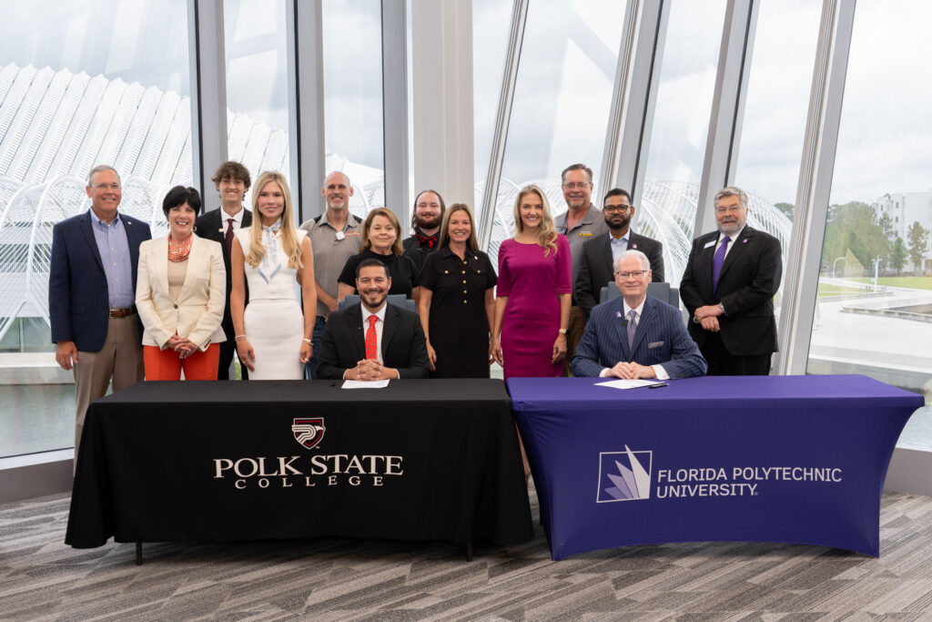 Polk State College President Anastasios Kamoutsas and Florida Polytechnic University President Devin Stephenson sign an expanded transfer agreement July 30 at Florida Poly’s Barnett Applied Research Center, joined by legislators, trustees, industry representatives and students.