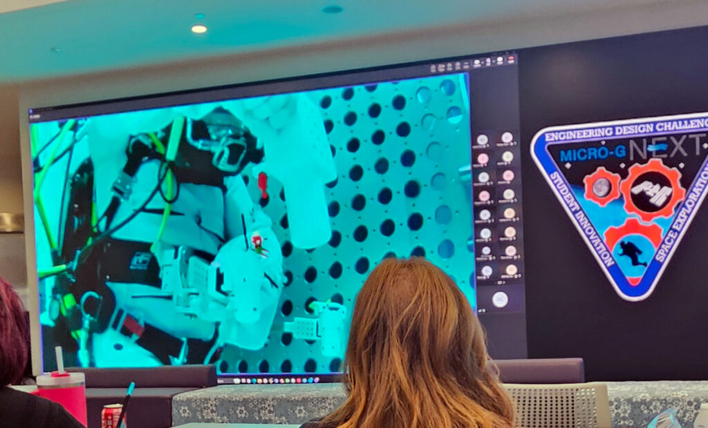 Florida Polytechnic University employees watch the live broadcast of a NASA diver performing an underwater test of the University’s student-designed tool dock as part of NASA’s Micro-g NExT Challenge.