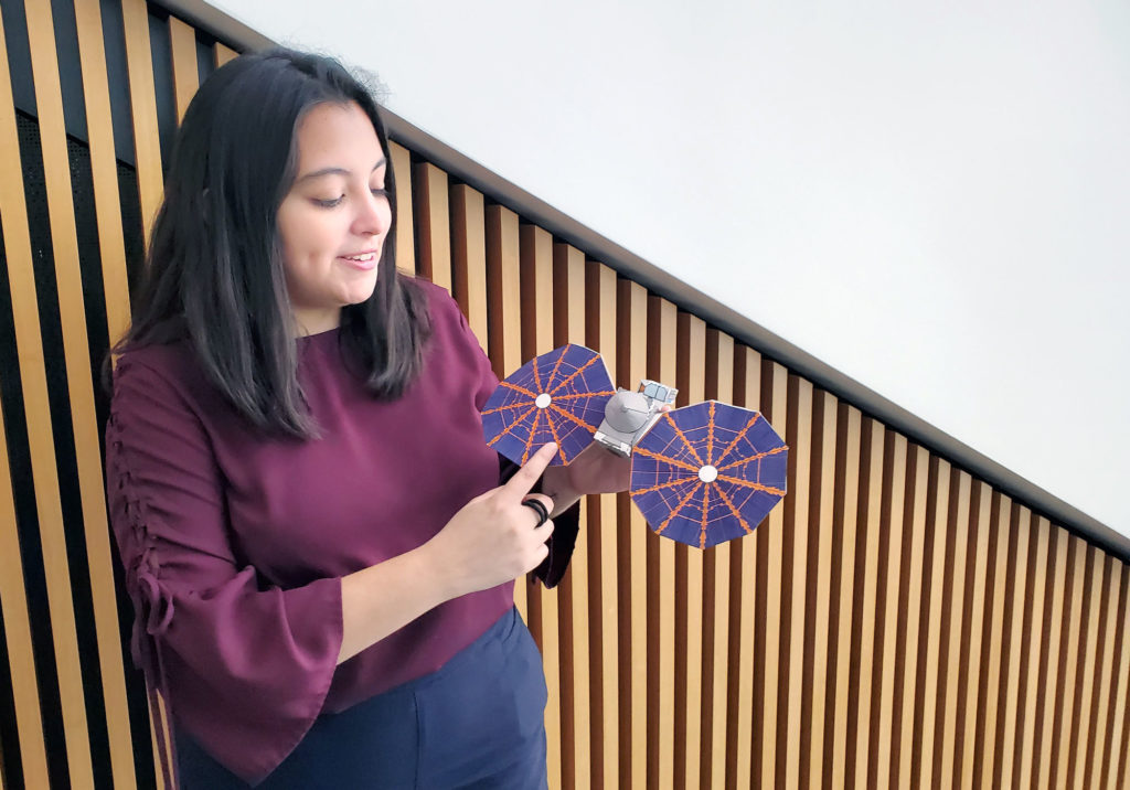 Mechanical engineering major Elise Araiza shows a model of Lucy, a planned NASA space probe that will travel to Jupiter’s Trojan asteroids to collect data and images.