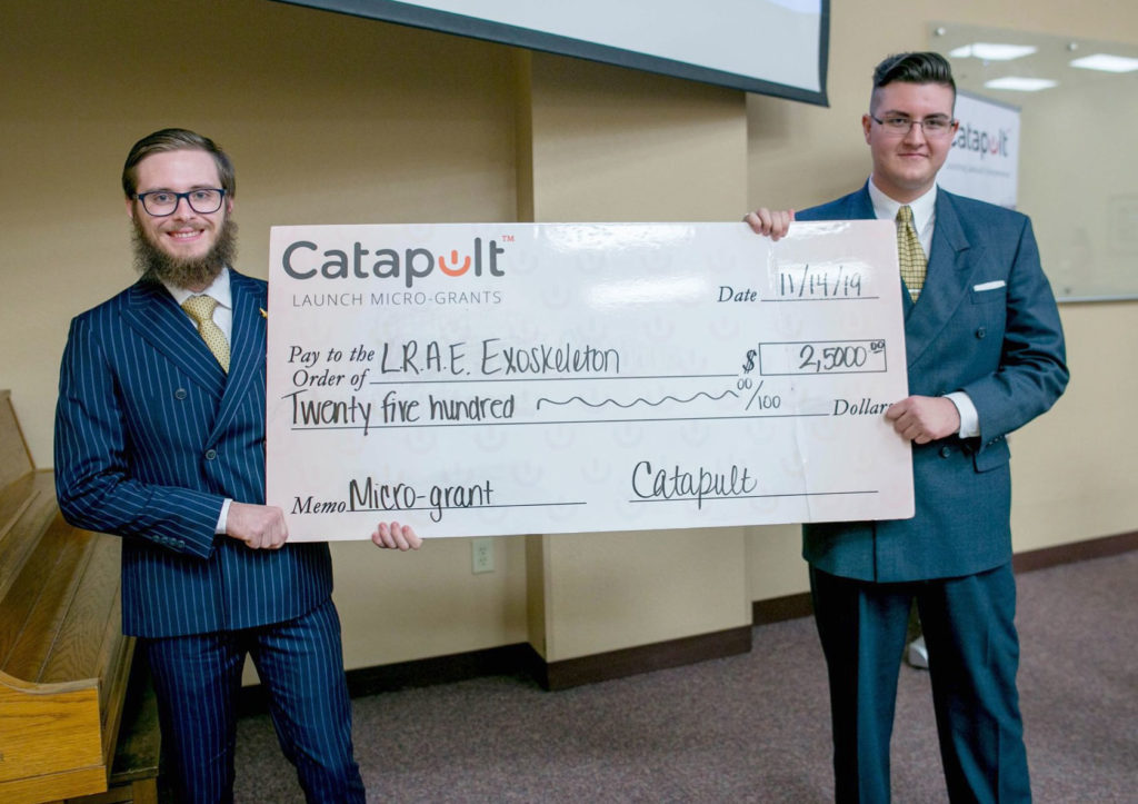 Two light skinned males holding up giant check