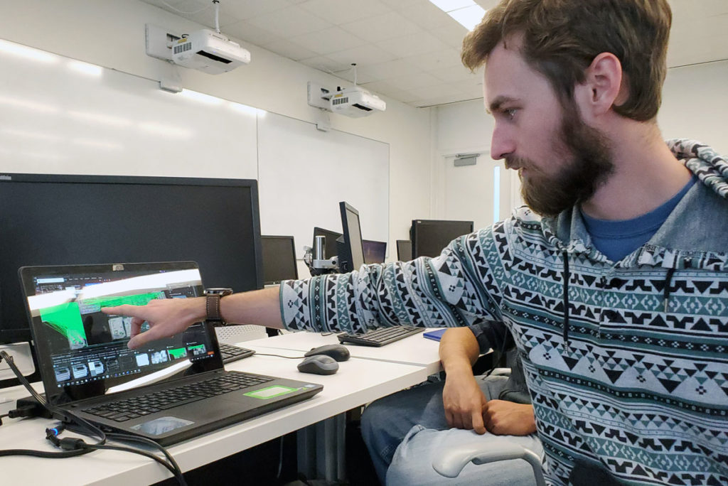 Light skinned male pointing at computer screen.