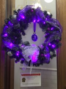 Wreath decorated with purple ornaments and lights.