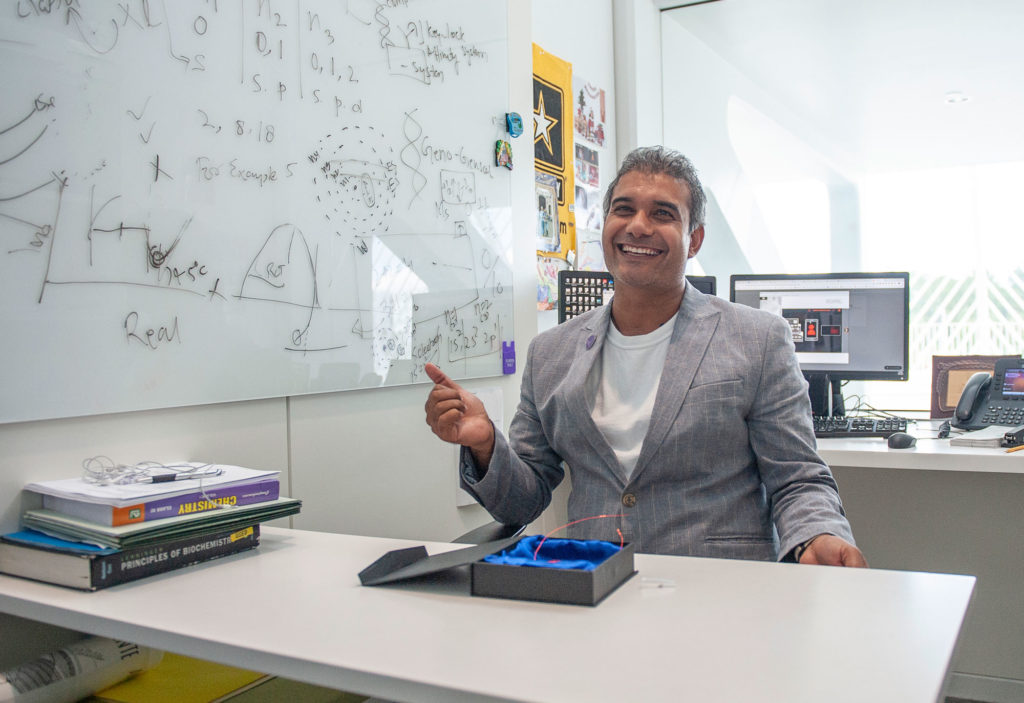 Medium skinned male smiling in office.