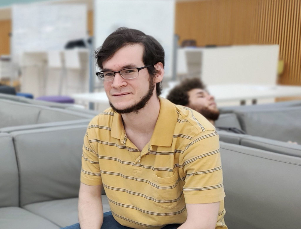 Light skinned male sitting on a couch.