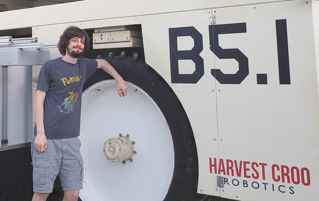 Light skinned male standing next to a truck.