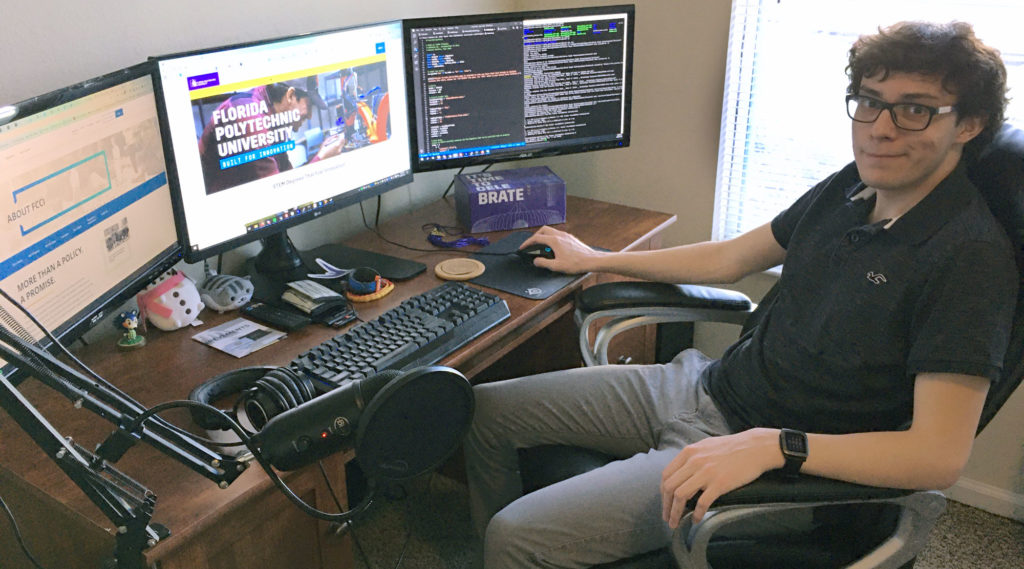 Light skinned male stilling in front of three computer screens.