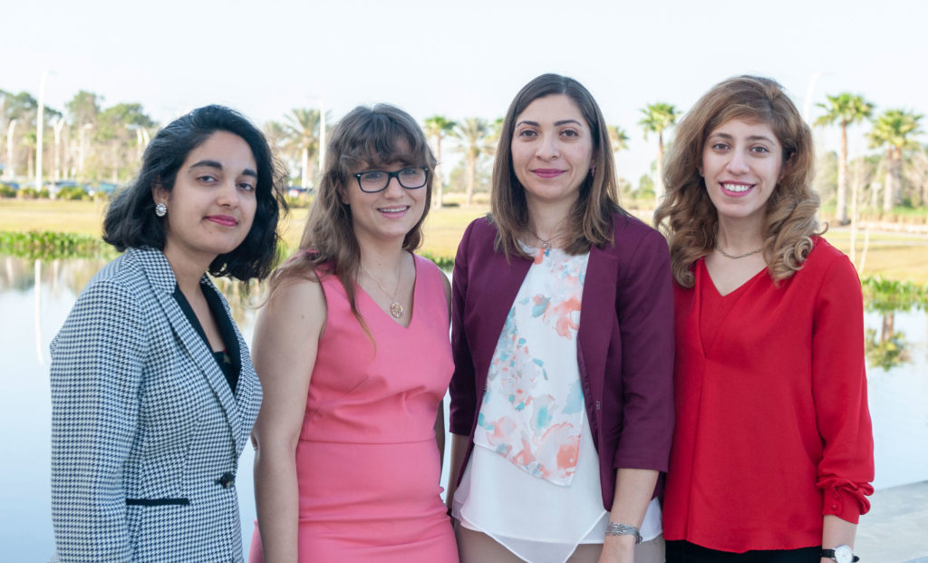 Four light skinned women standing together.