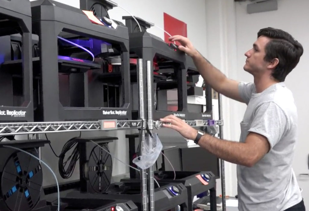 Light skinned male looking at a 3D printer.