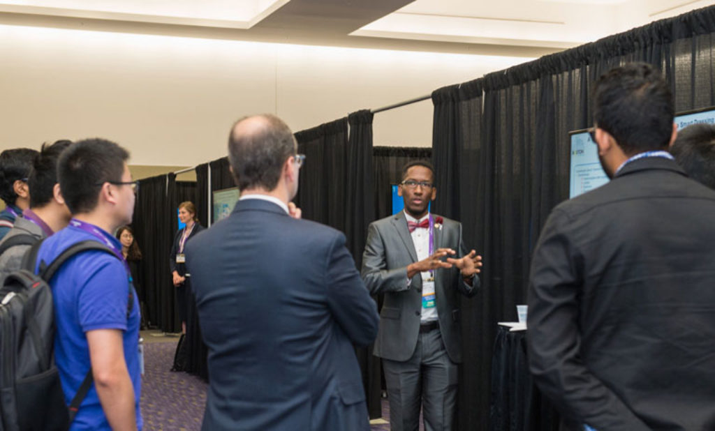Dark skinned male presenting to a room of people.