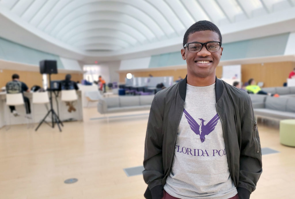Dark skinned male student with glasses standing in IST commons.