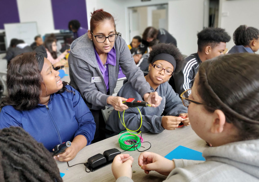Group of students in a class room looking at tool.