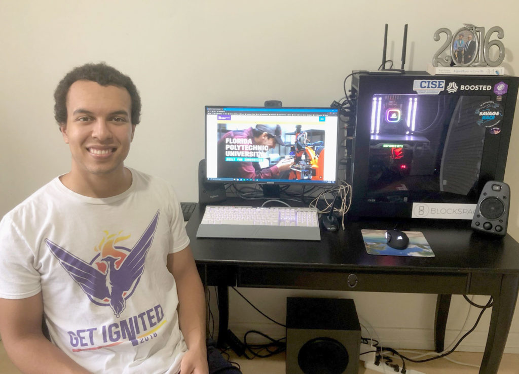 Light skinned male sitting in front of a computer.