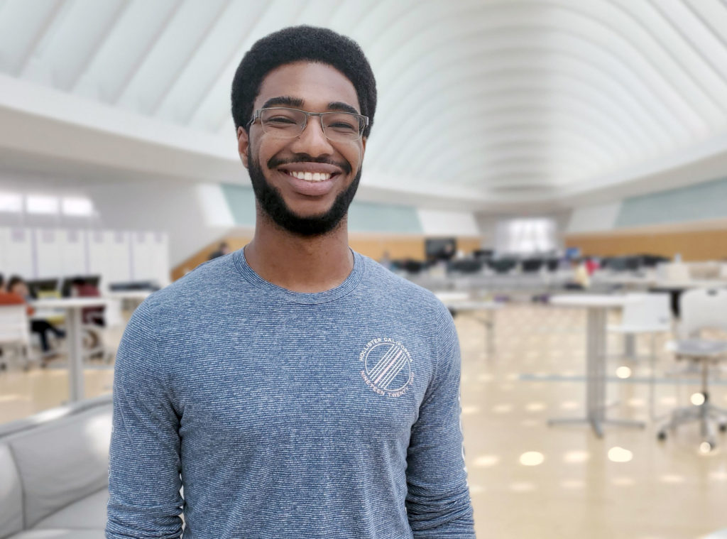Dark skinned male smiling inside building.