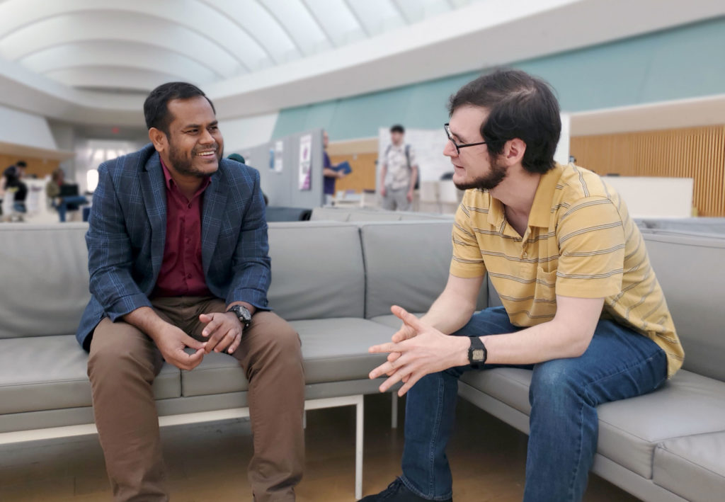 Male faculty and student sitting on a couch.