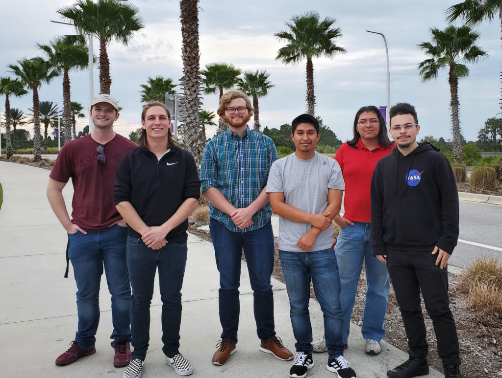 Group of students outside with palm trees.
