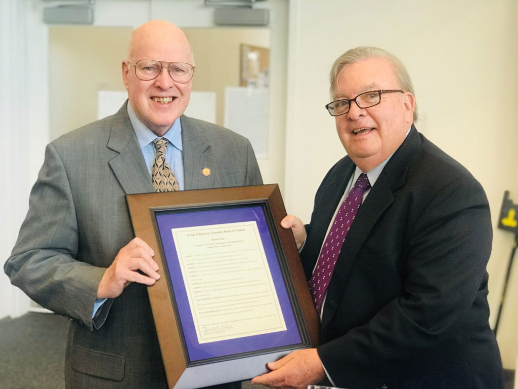 Two light skinned males holding a framed picture.