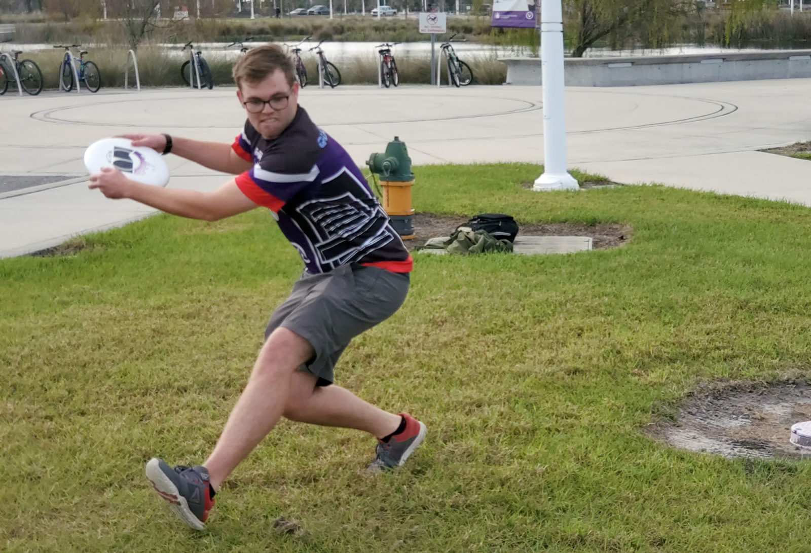 Light skinned male throwing frisbee outside.